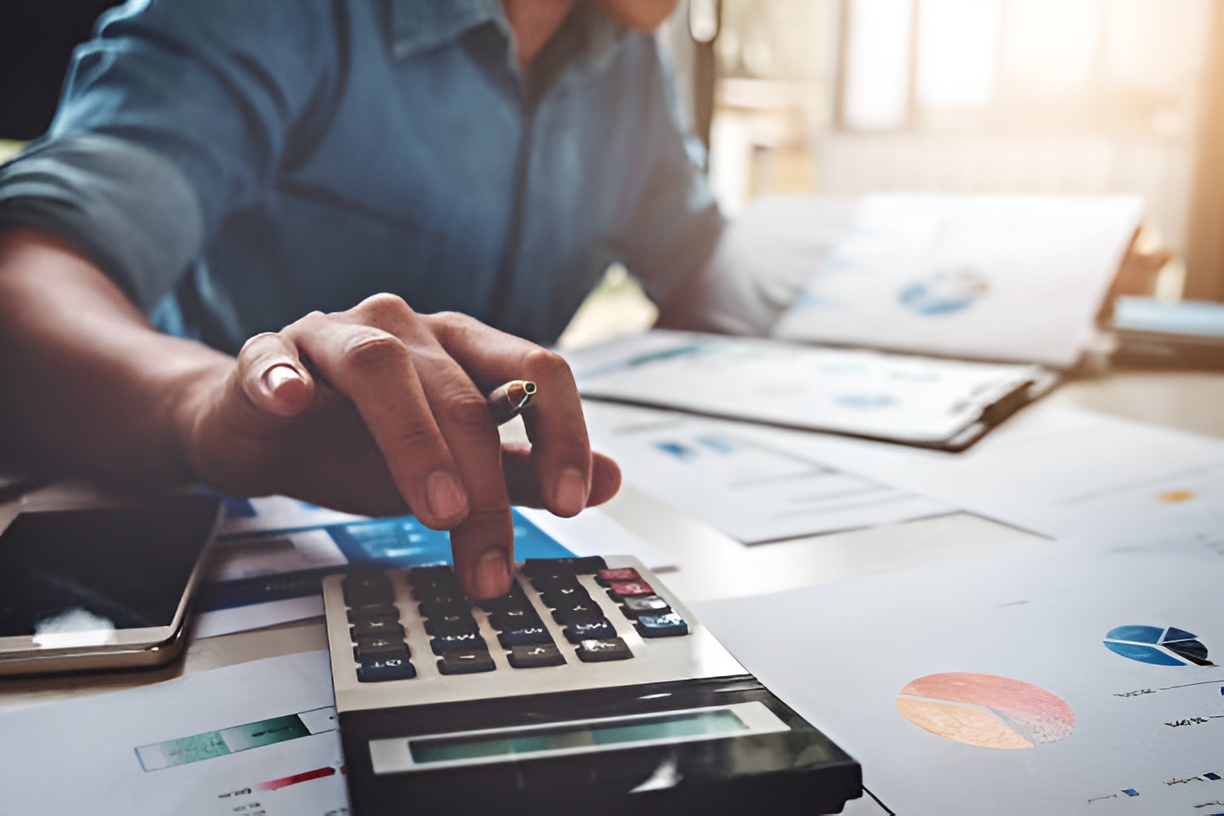 man using a calculator and working at a desk with business reports